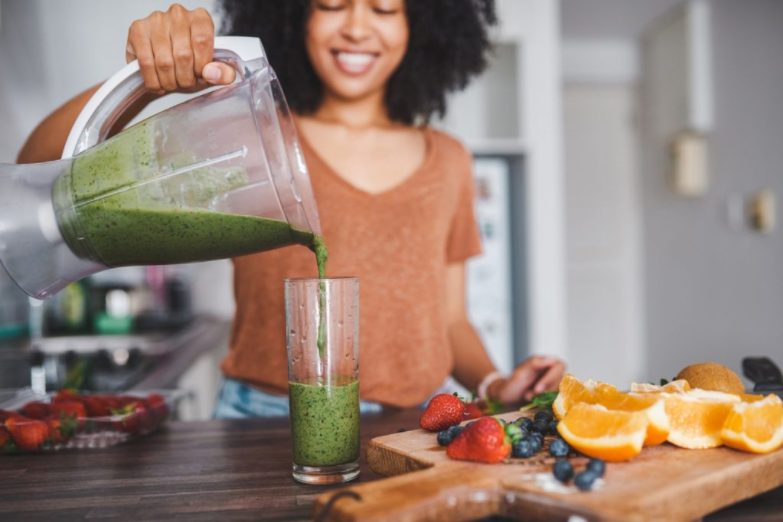 Young woman pouring smoothie to glass